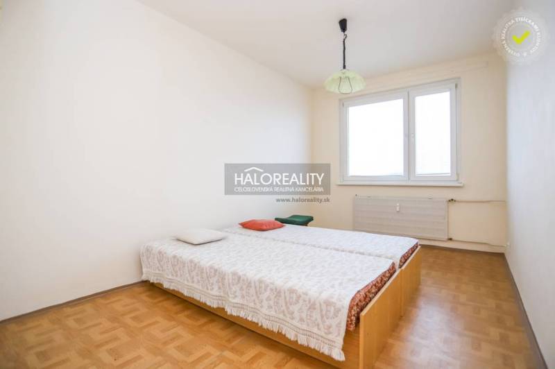 Ložnice ve 3pokojovém bytě s podlahou s dřevěným dekorem, postelí u okna.