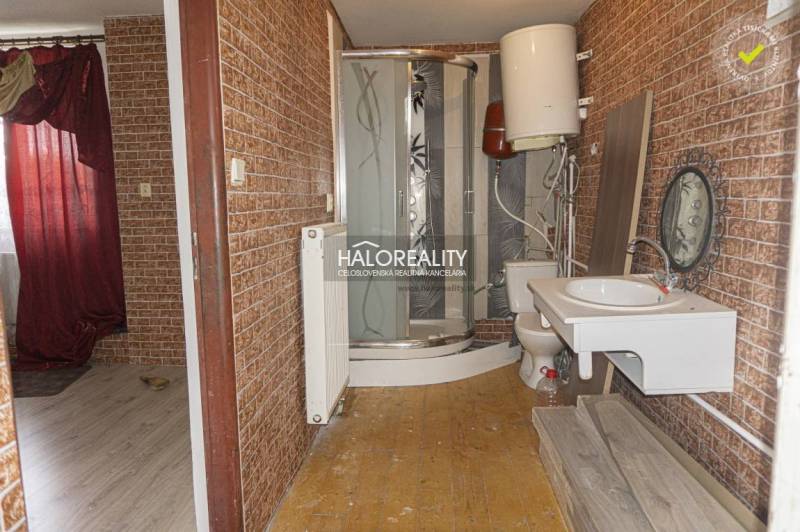 Koupelna v obchodních prostorách s dřevěným dekorem na stěnách a sprchovým koutem.