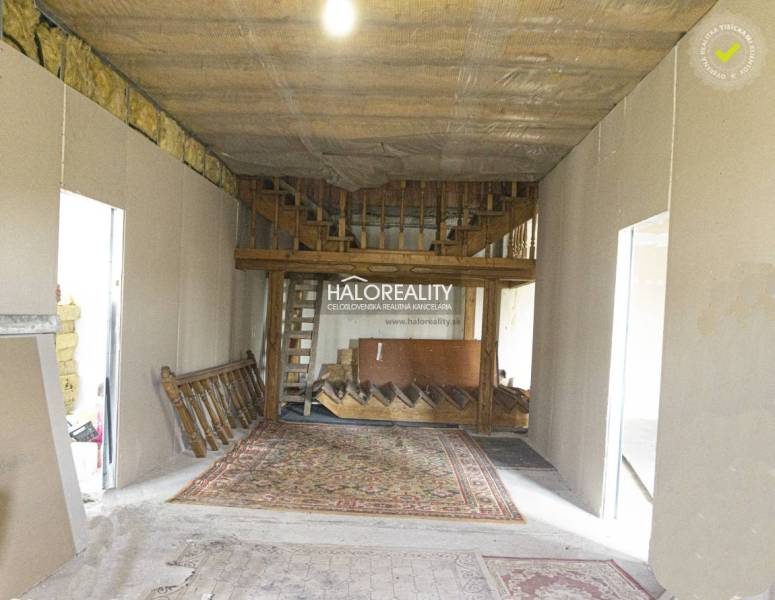 Interiér obchodních prostor s dřevěným schodištěm a kobercem.