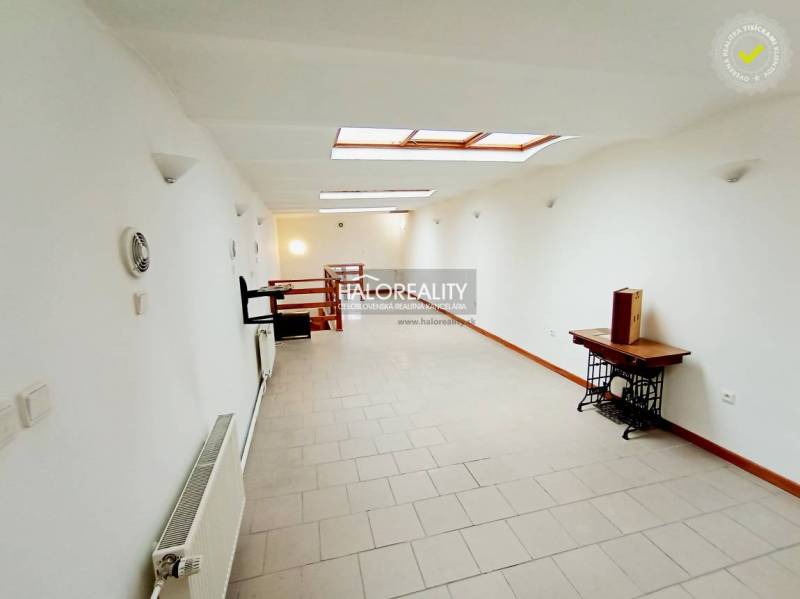 Světlá chodba v rodinném domě s bílými stěnami a střešními okny.