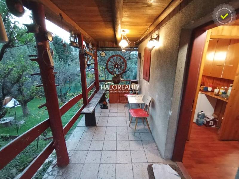 Venkovní terasa s dřevěným zábradlím a zahradou u chaty, nabízí klid.