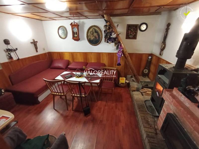 Rustikální chata, dřevěný strop, krb, pohodlná sedací souprava, tradiční interiér, příjemná atmosféra.