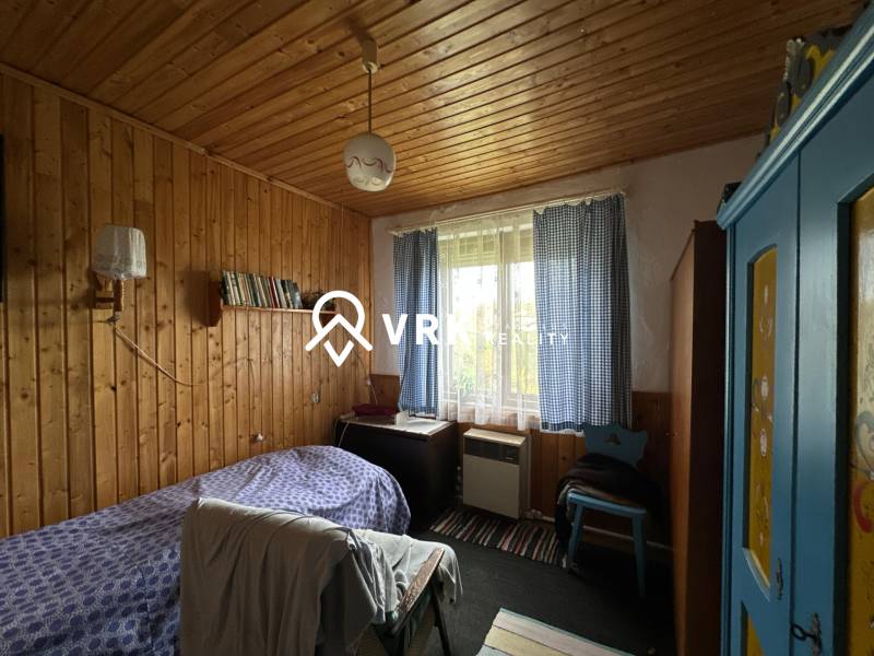 Pokoj v rodinném domě s dřevem obloženými stěnami, modrou skříní a postelí.