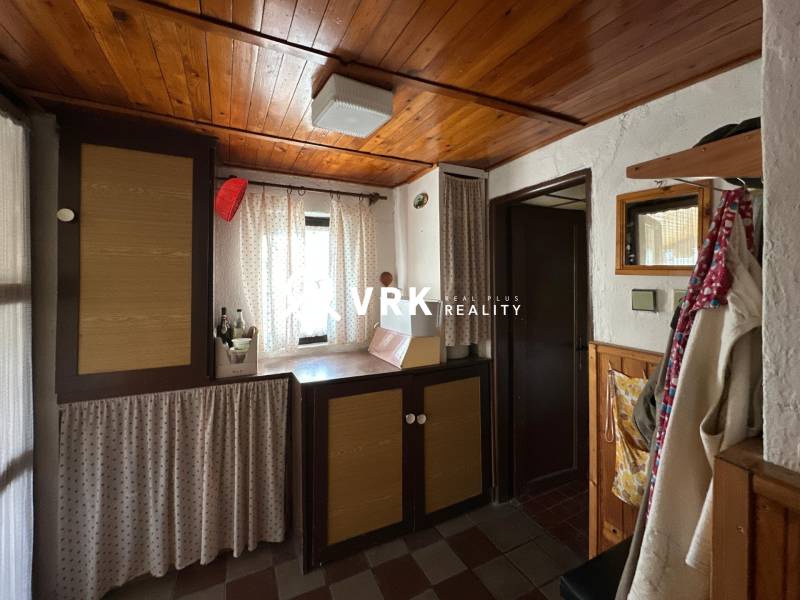 Interiér rodinného domu s dřevěným stropem a závěsy, útulný koutek s dekoračními prvky.