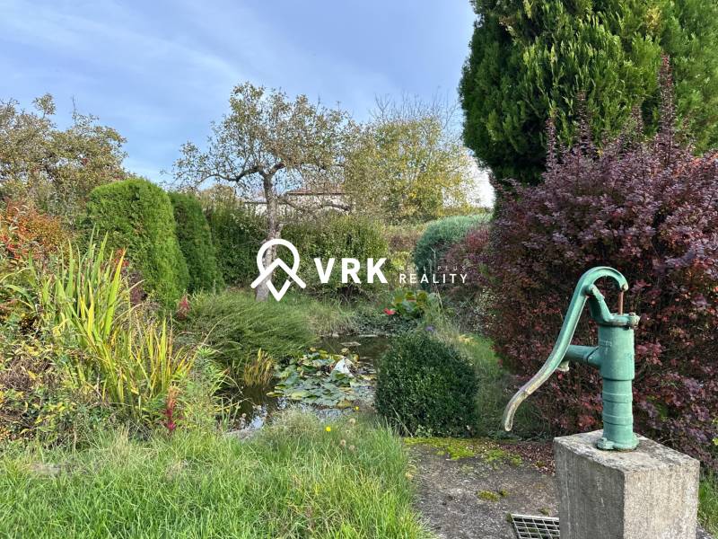 Zahrada rodinného domu v Kalši se starou pumpou a velkým množstvím zeleně.