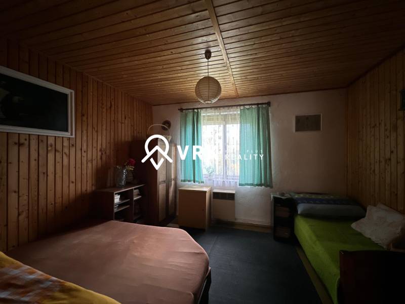 Pokoj s dřevěným obložením a postelemi v rodinném domě.