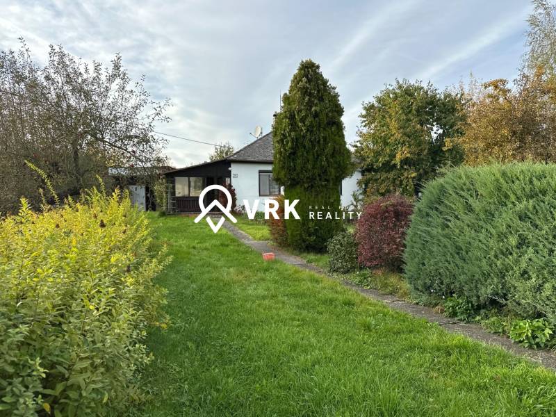 Rodinný dům v Kalši obklopený zahradou s různorodou vegetací.