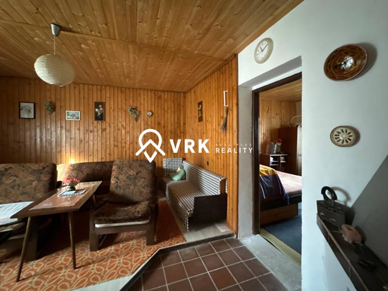 Interiér rodinného domu s dřevěným obkladem a pohodlným nábytkem s retro dekoracemi.