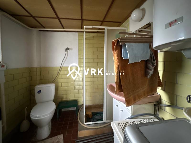 Koupelna v rodinném domě s toaletou, sprchovým koutem a umyvadlem.