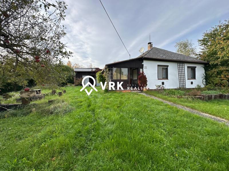 Rodinný dům v Kalši obklopený zahradou a ovocnými stromy, s upraveným trávníkem.