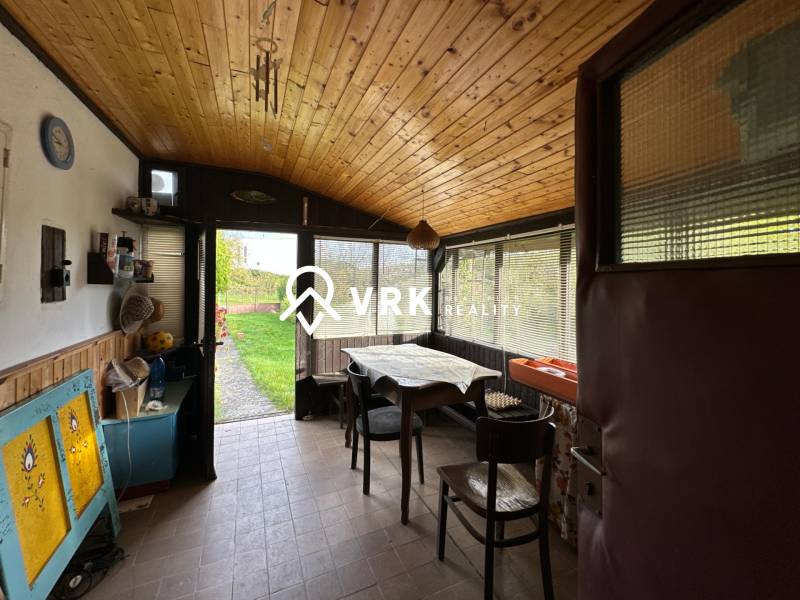 Interiér rodinného domu s podlahou s dřevěným dekorem, jídelním stolem a výhledem do zahrady.