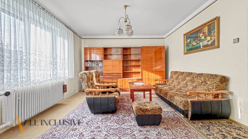 Obývací pokoj v rodinném domě s koberci, nábytkem a křesly, s dekorativním obrazem.