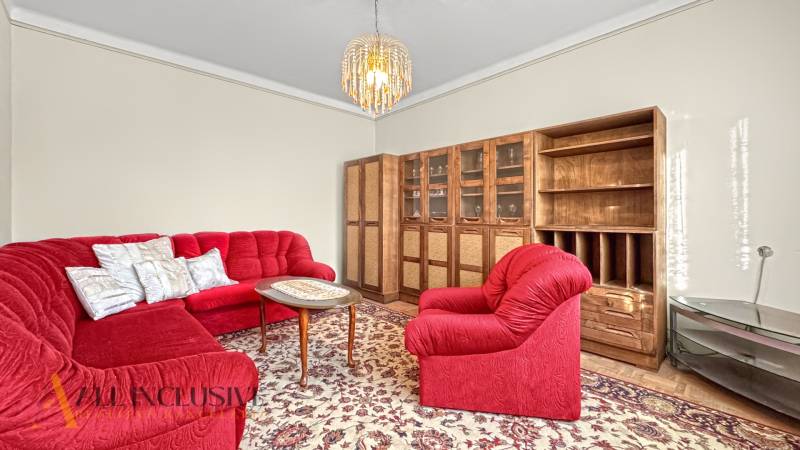 Obývací pokoj rodinného domu s červenou sedací soupravou a dřevěnou sestavou.