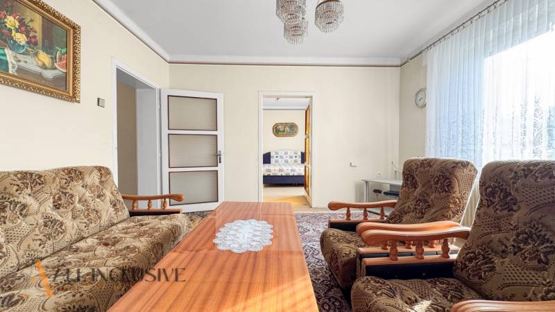 Rodinný dům s obývacím pokojem, květinovým nábytkem, konferenčním stolkem a obrazem na stěně.