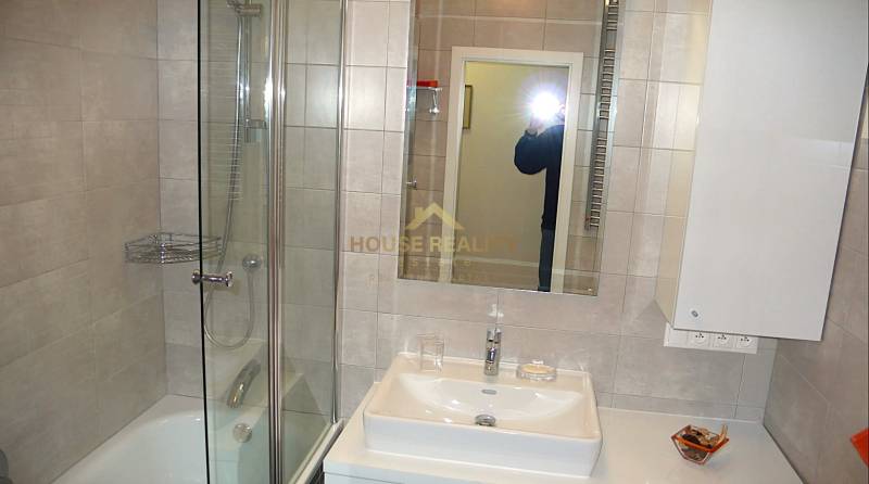 Koupelna se sprchou, zrcadlem a umyvadlem ve 4-pokojovém bytě.