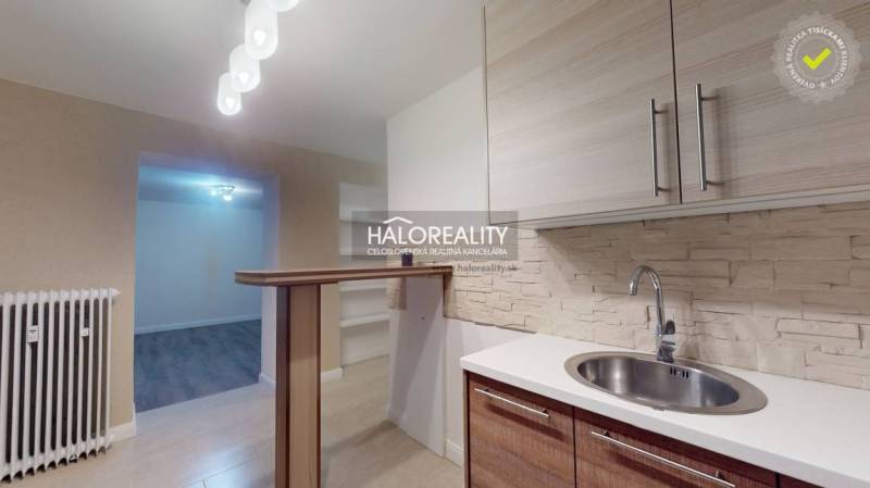 Kuchyně 2pokojového bytu s podlahou s dřevěným dekorem a barovým pultem.