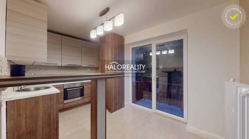 Kuchyně v 2-pokojovém bytě s podlahou s dřevěným dekorem a vstupem na balkon.