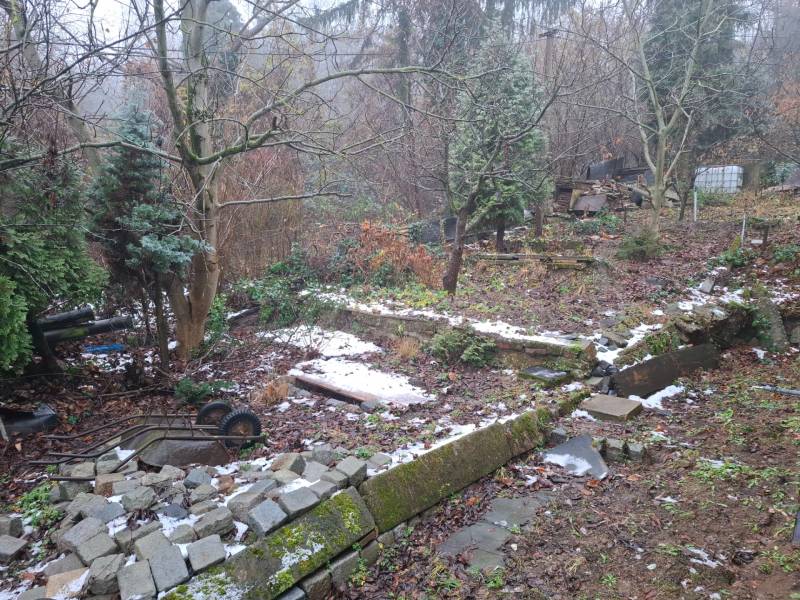 Zahrada u rodinného domu na Búdkové v Bratislavě - Staré Město, s rozbitým plotem a stromy.