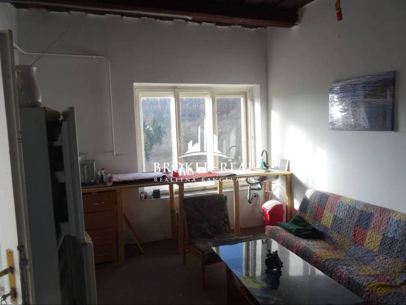 Obývací pokoj s pohovkou a výhledem ven, Rodinný dům s jednoduchým zařízením.