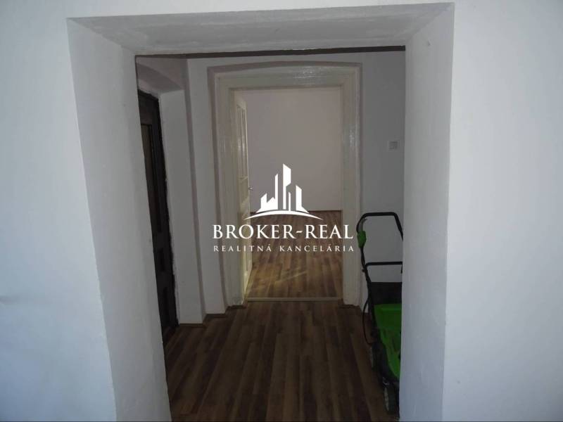 Chodba rodinného domu s podlahou s dřevěným dekorem a výhledem do další místnosti.