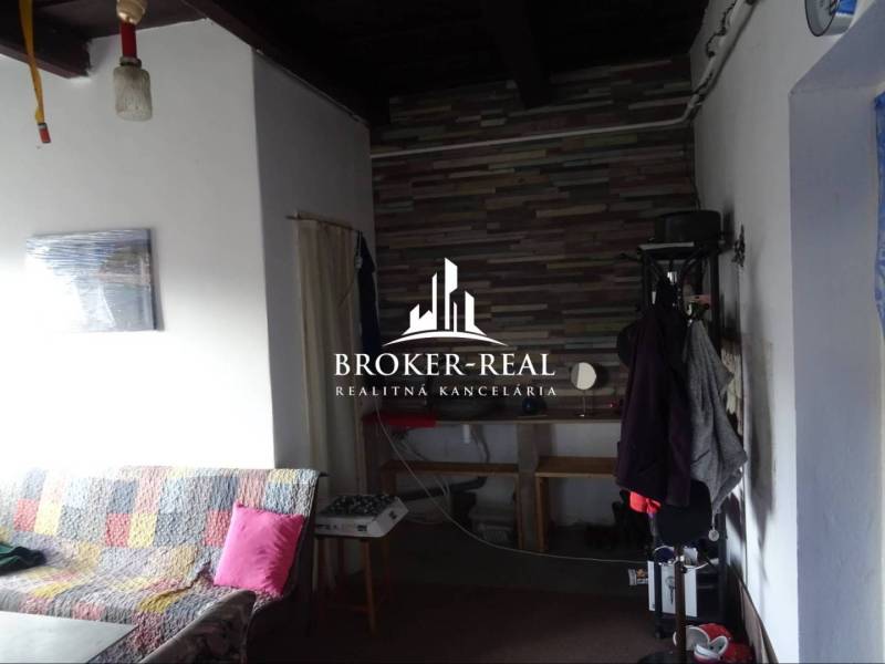 Interiér rodinného domu s pohovkou a věšákem, obložená stěna v pozadí.