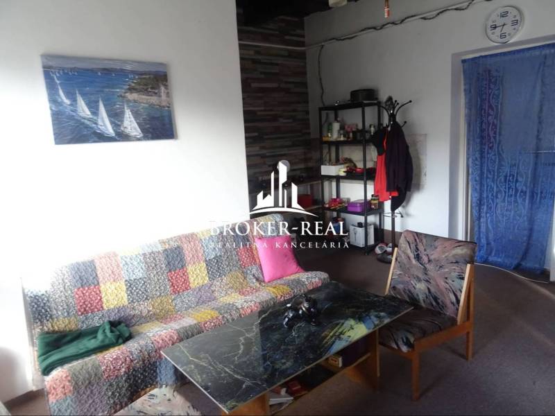 Obývací pokoj v rodinném domě s barevnou sedačkou, konferenčním stolkem a nástěnným obrazem.