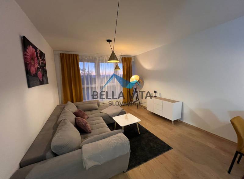 Obývací pokoj v 2pokojovém bytě s pohovkou a podlahou s dřevěným dekorem.