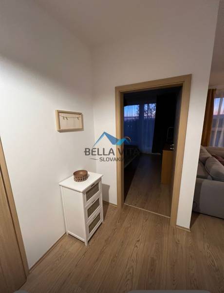 Interiér 2-pokojového bytu s podlahou s dřevěným dekorem, světlý nábytek a dekorace.