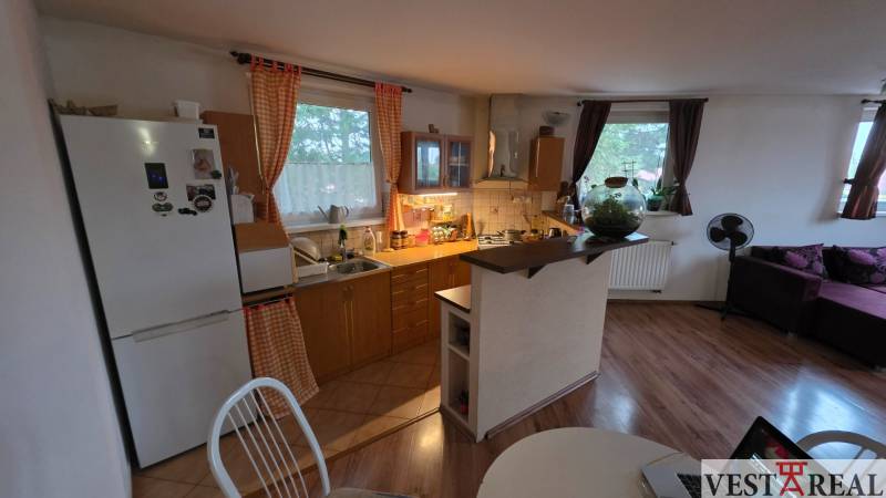 Kuchyně ve 3-pokojovém bytě s podlahou s dřevěným dekorem a jídelním stolem.