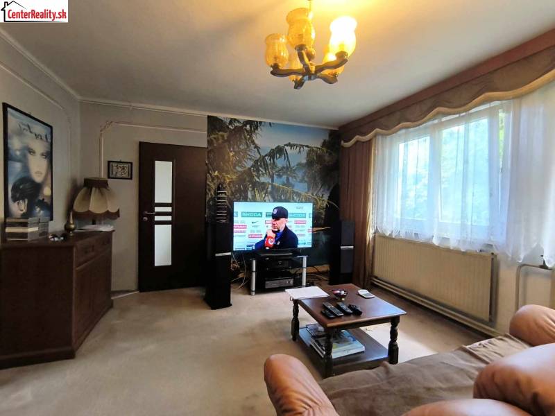 Obývací pokoj s televizí, sedačkou, stolkem a velkým oknem, Rodinný dům.