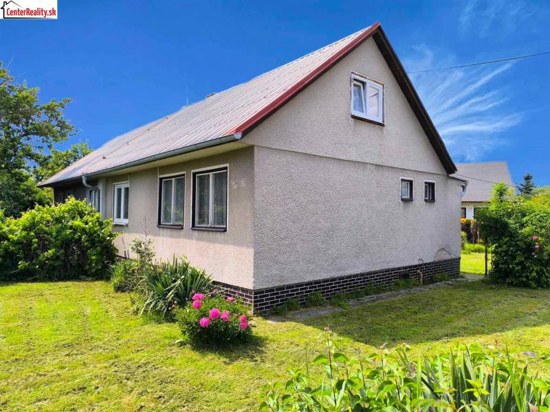 Rodinný dům v Novácích s bílou fasádou a zahradou plnou zeleně.