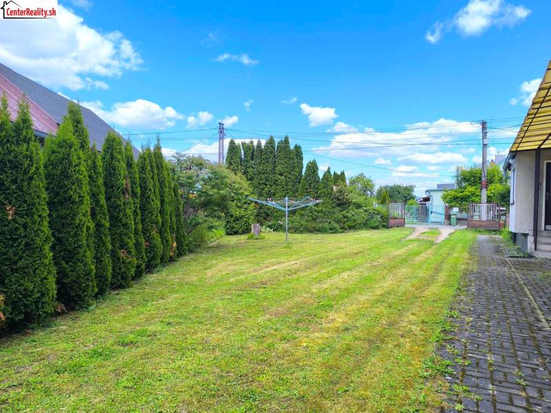 Zahradní plocha rodinného domu v Prievidzi s pečlivě udržovaným trávníkem a živým plotem.