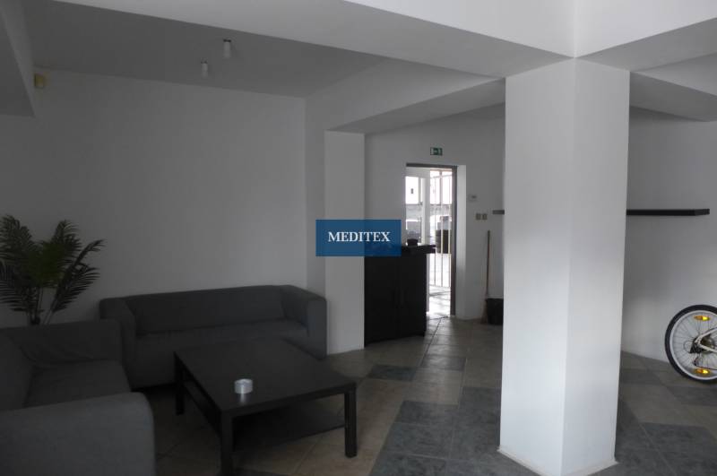 Obývací prostor s šedými pohovkami, stolkem a dlaždicovou podlahou ve skladech a halách.