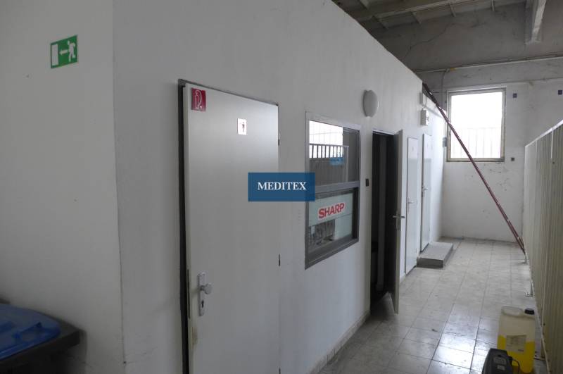 Interiér s bílými dveřmi a šedými stěnami ve skladových a halových prostorách.