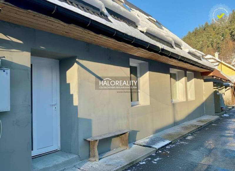 Rodinný dům v Hronci se sněhem na střeše, bílými dveřmi a dřevěnou lavičkou.