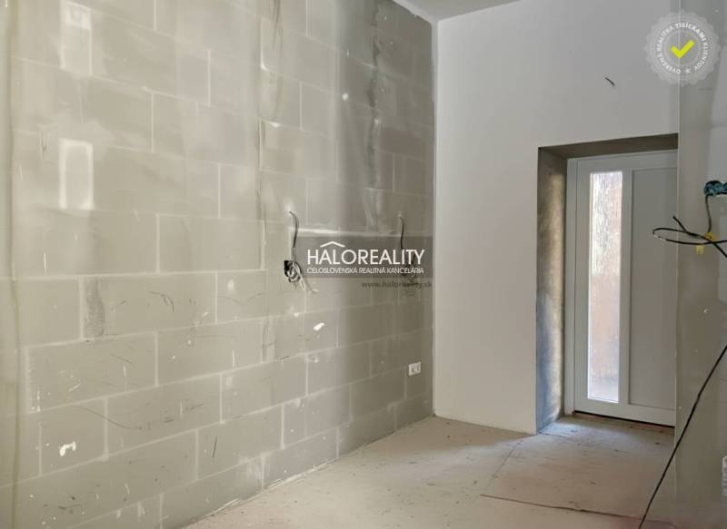 Světlá místnost s nedokončenými stěnami v rodinném domě se vstupními dveřmi.