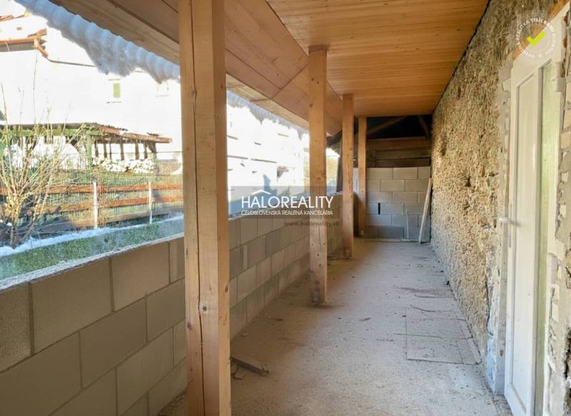 Zastavěný prostor rodinného domu v Hronci se stěnami z kamene a dřevěnými nosníky.