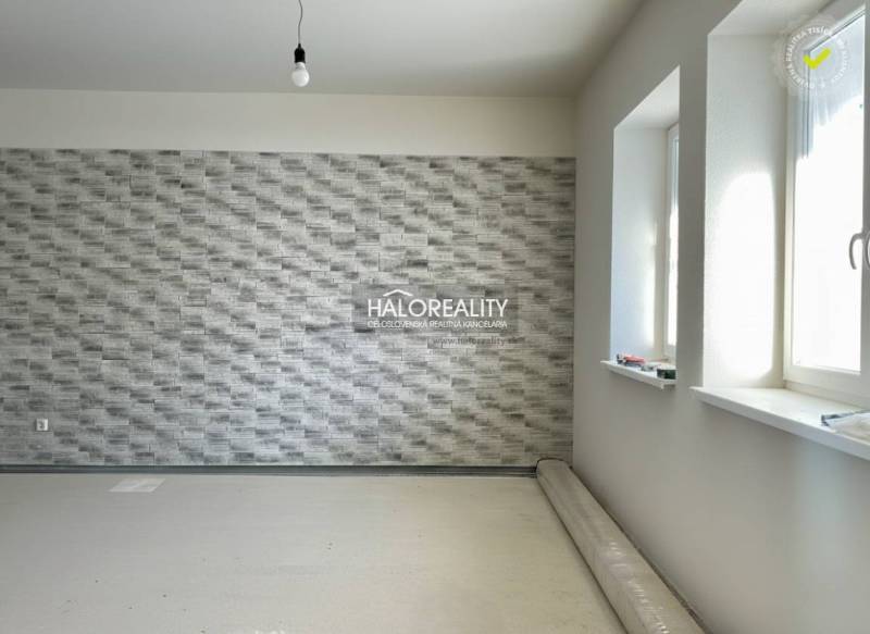 Interiér rodinného domu s texturovanou stěnou a nenainstalovanou podlahou s dřevěným dekorem.