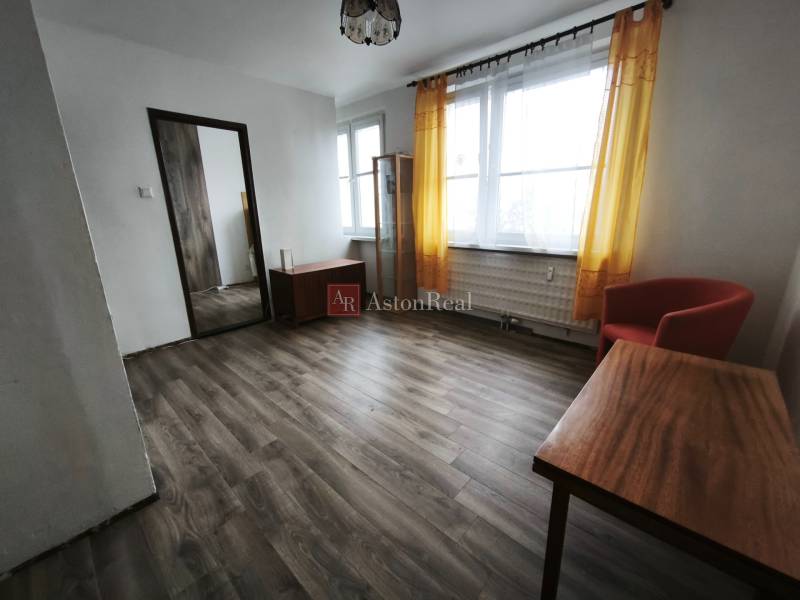 Obývací pokoj v garsonce s podlahou s dřevěným dekorem a žlutými závěsy.