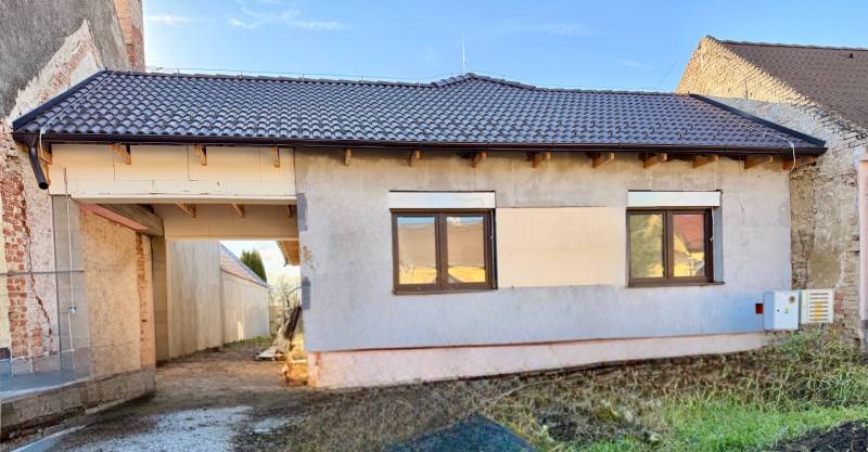 Rodinný dům v Cíferi s neomítnutou fasádou a hnědou střešní krytinou.