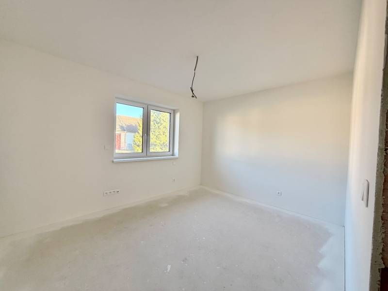 Prostorný, světlý pokoj v rodinném domě s dvojitým oknem a bílými stěnami.