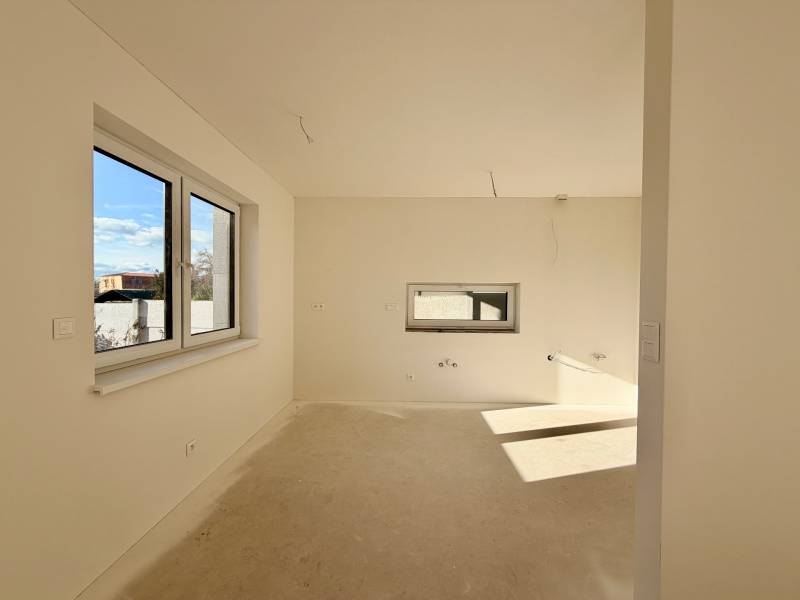 Interiér rodinného domu bez podlahy a s okny na slunečné straně.