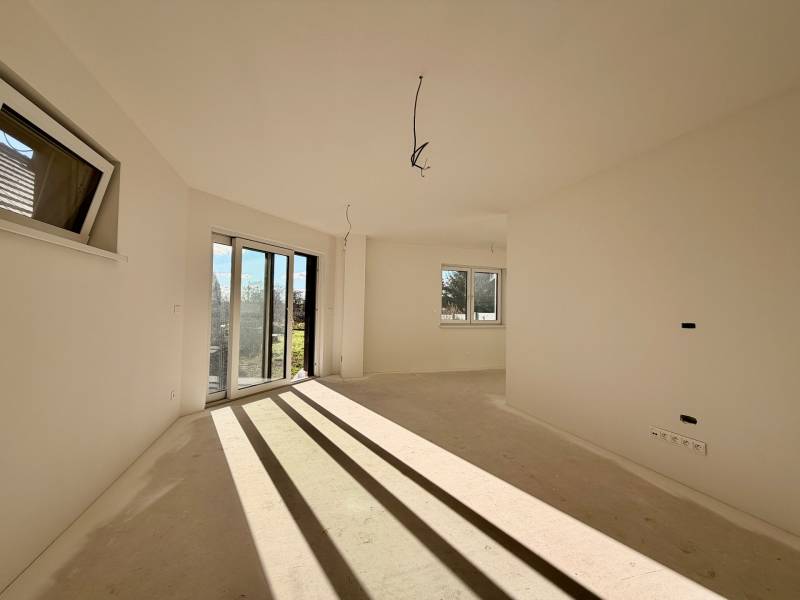 Prostorná místnost v rodinném domě s velkými okny a výhledem do zahrady.