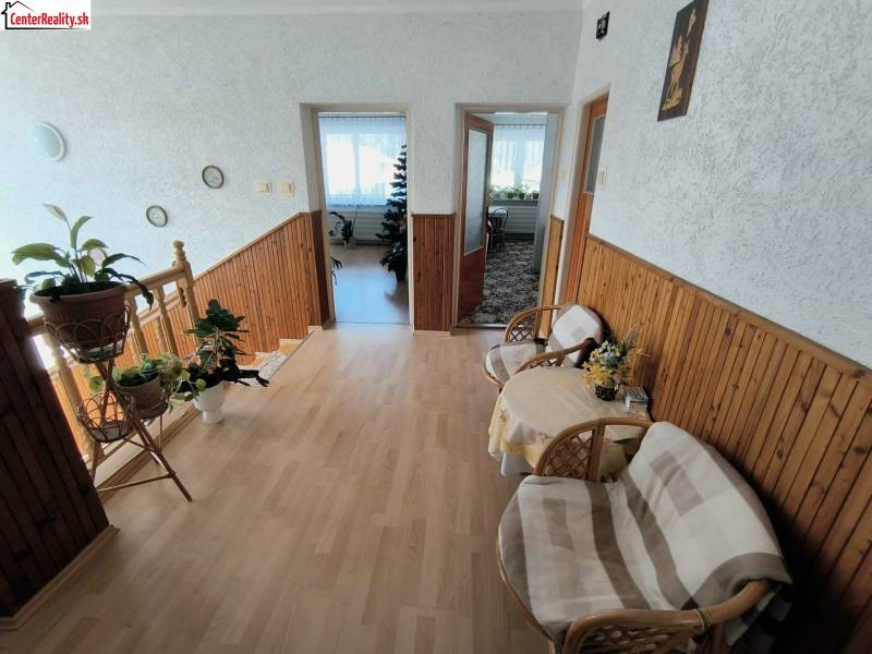 Interiér rodinného domu se schodištěm, podlahou s dřevěným dekorem a prostornou předsíní.