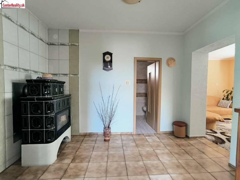 Interiér rodinného domu se zelenými kachlemi, kachlovými kamny a dlažbou.