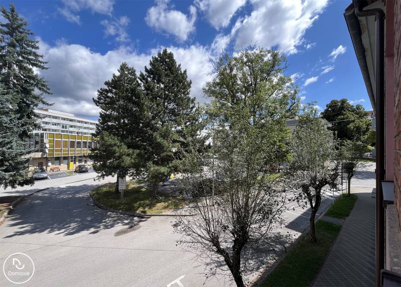 Pohled z 5 a více pokojového bytu na ulici Medveckého v Ružomberku, obklopený stromy.