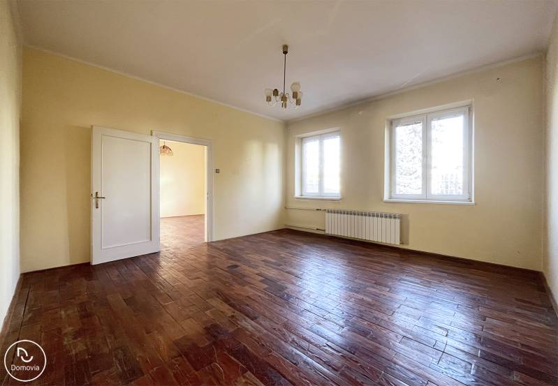 Prostorný pokoj s podlahou s dřevěným dekorem a dvěma velkými okny.