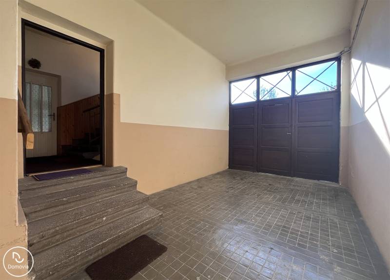 Vstupní hala s garážovými dveřmi v bytě s 5 a více pokoji, schody vedou do interiéru.