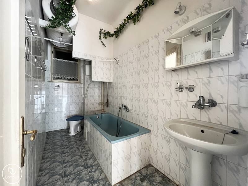 Koupelna s vanou, bílými kachličkami a zelenou dekorací v 5 a více pokojovém bytě.