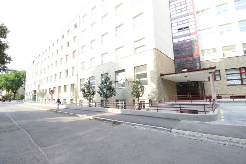 Budova na Bezručově ulici v Bratislavě - Starém Městě s rampou a stromy.